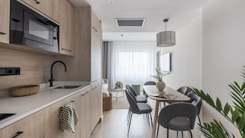 Una cocina moderna con microondas integrado, un lavamanos y una zona de comedor con mesa y sillas.