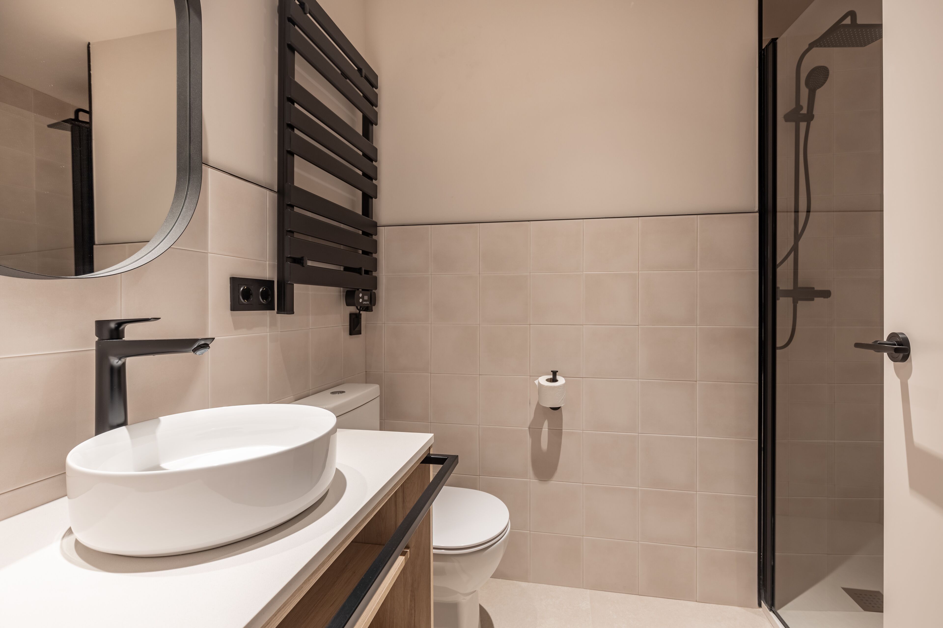 Un baño moderno con un lavabo ovalado grande, un inodoro y una zona de ducha con paredes de vidrio.