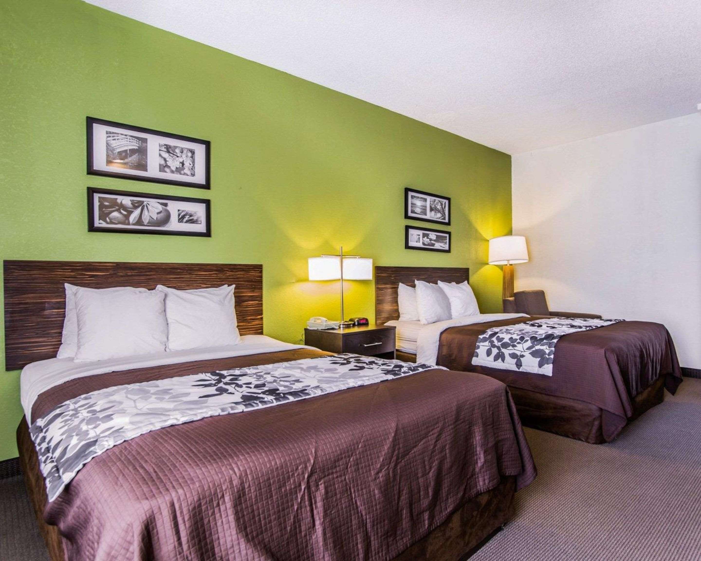 A hotel room with two beds, green walls, and framed pictures on the wall.