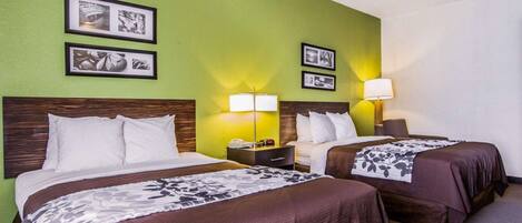 A hotel room with two beds, green walls, and framed pictures on the wall.