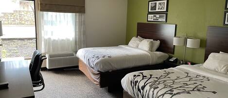 A hotel room with two beds, a desk, and a chair.