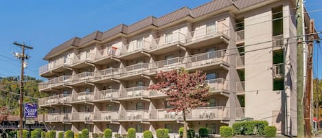 A multi-story hotel with balconies, a sign indicating it is a Sleep Inn, and a clear blue sky.