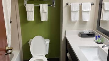 Un baño con pared verde, inodoro blanco y lavabo con espejo.