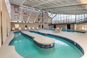 An indoor swimming pool with clear blue water, surrounded by lounge chairs and a covered seating area.