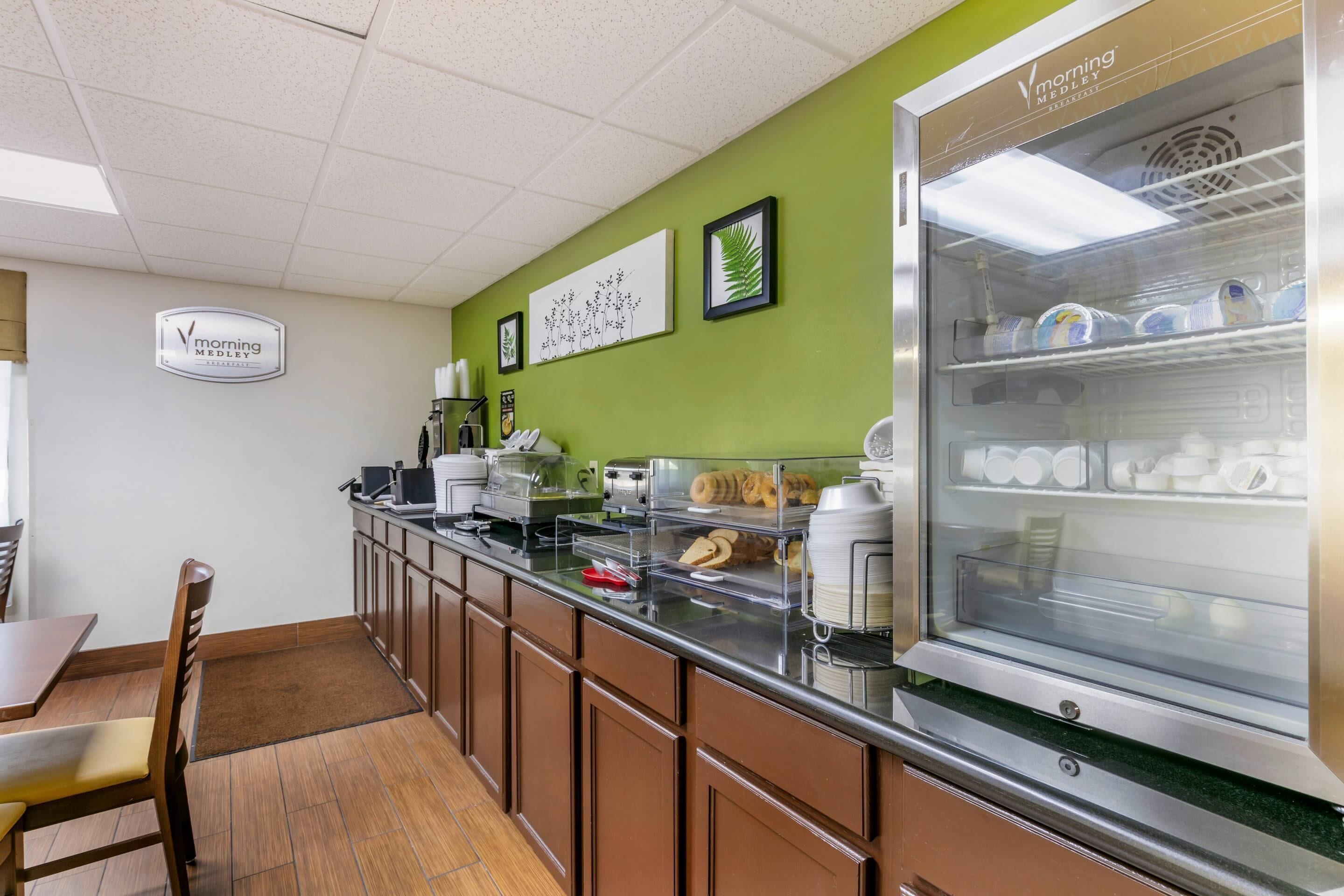 A breakfast bar with a refrigerator displaying milk cartons, a coffee machine, and a bread display.