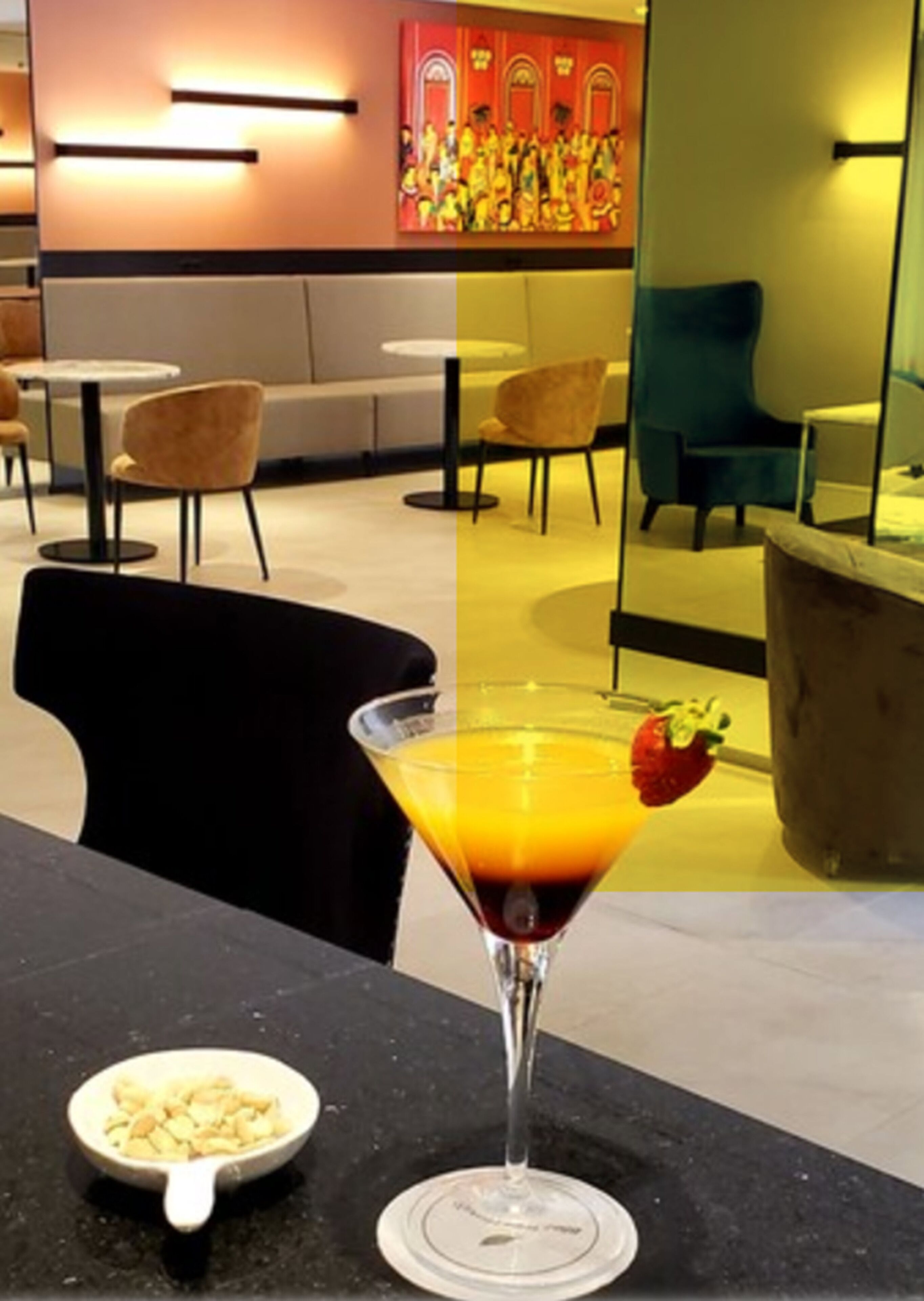 Zona de bar con una copa de martini que contiene un cóctel, un cuenco de frutos secos y un mural colorido de fondo.
