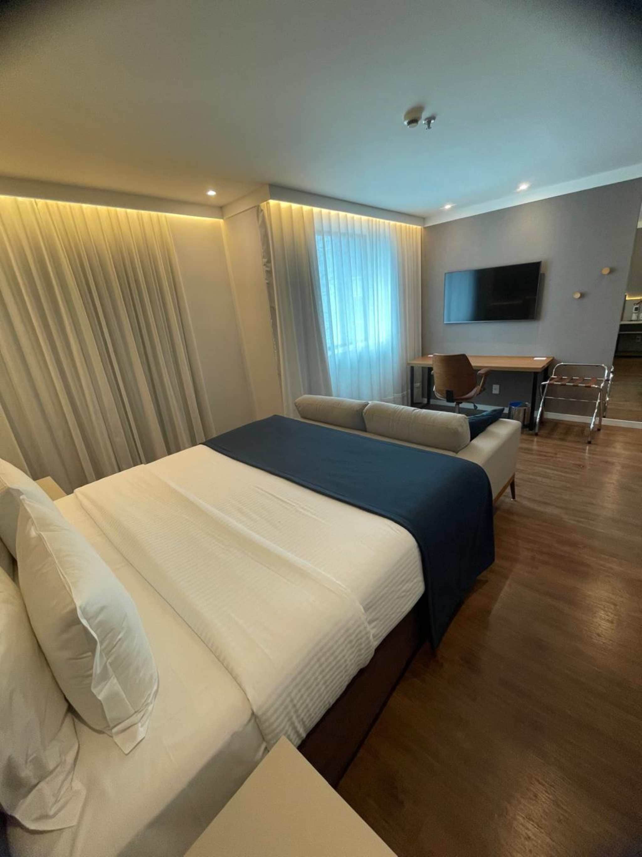 A hotel room with a large bed, a desk, and a TV.