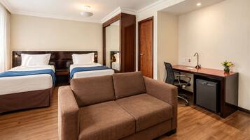 Habitación de hotel con dos camas, un sofá, un escritorio y una silla.
