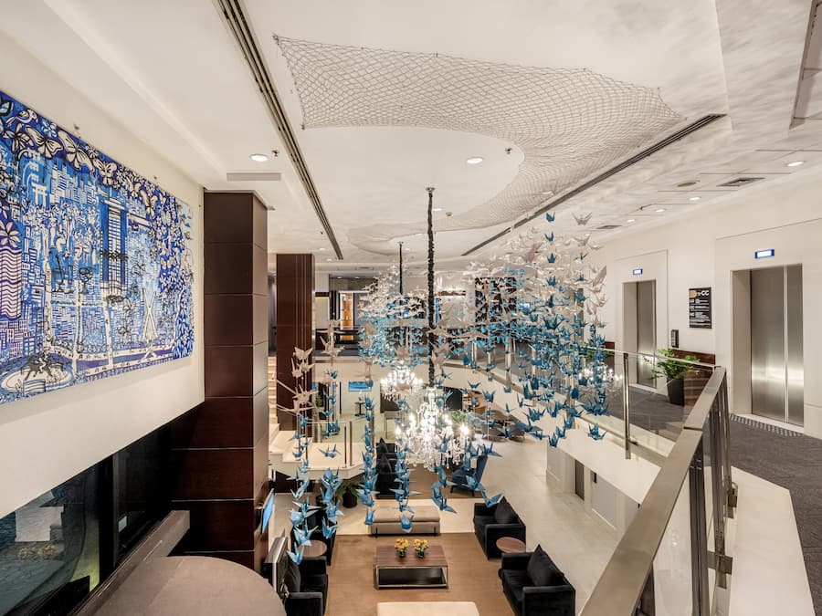 A modern lobby with a large blue mural, a chandelier, and a seating area.