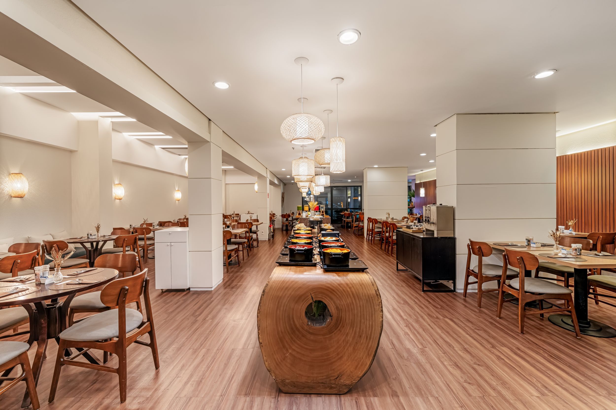 Un restaurante amplio con suelo de madera, varias mesas de comedor y una zona de buffet central.