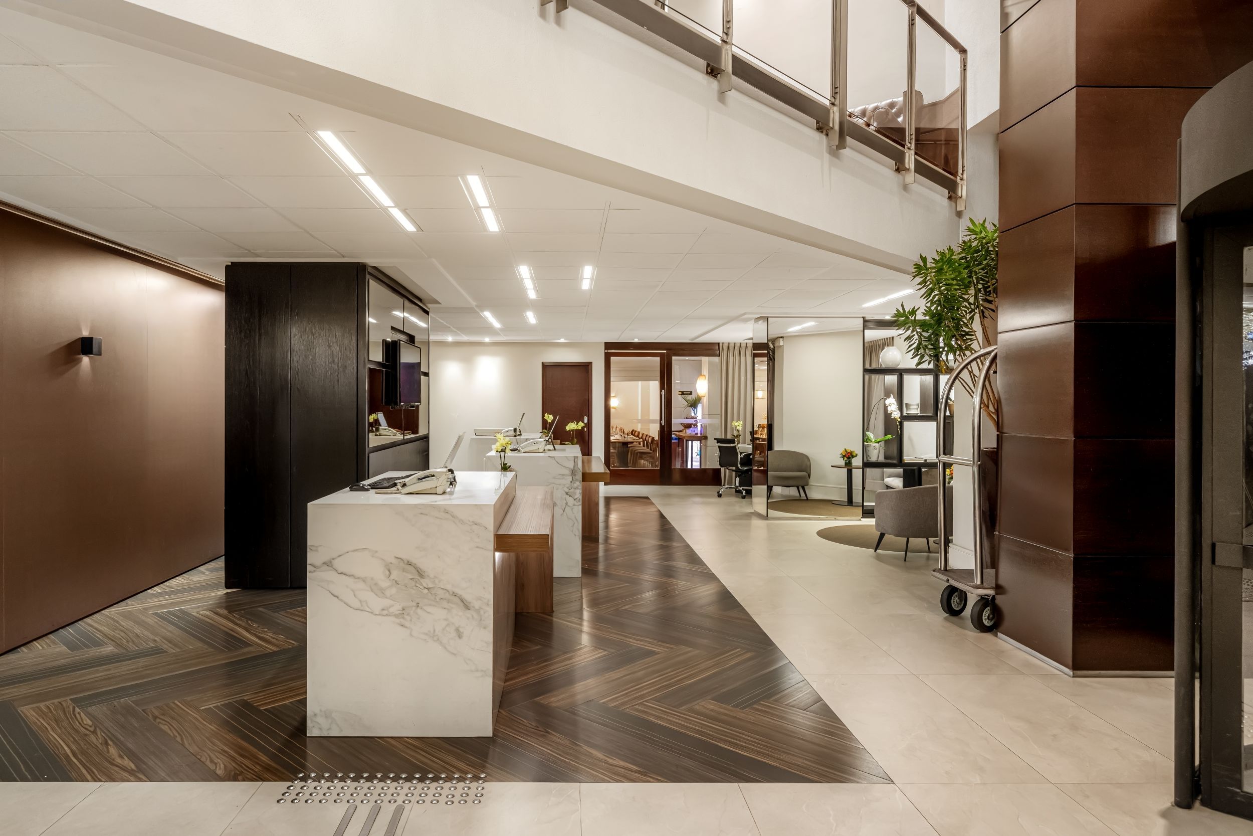 Eine geräumige Lobby mit einem Marmor-Empfangsschalter, einer Sitzecke und einer Treppe zu einer oberen Ebene.