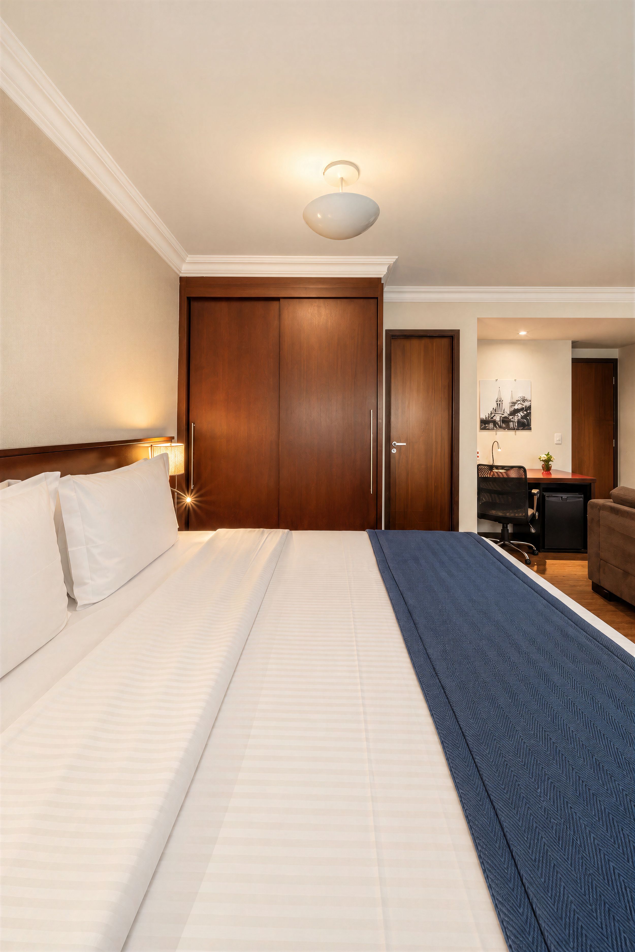 Ein Hotelzimmer mit einem großen Bett, einem Schreibtisch, einem Stuhl und einem Kleiderschrank.