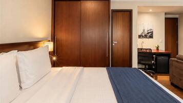 Ein Hotelzimmer mit einem großen Bett, einem Schreibtisch, einem Stuhl und einem Kleiderschrank.