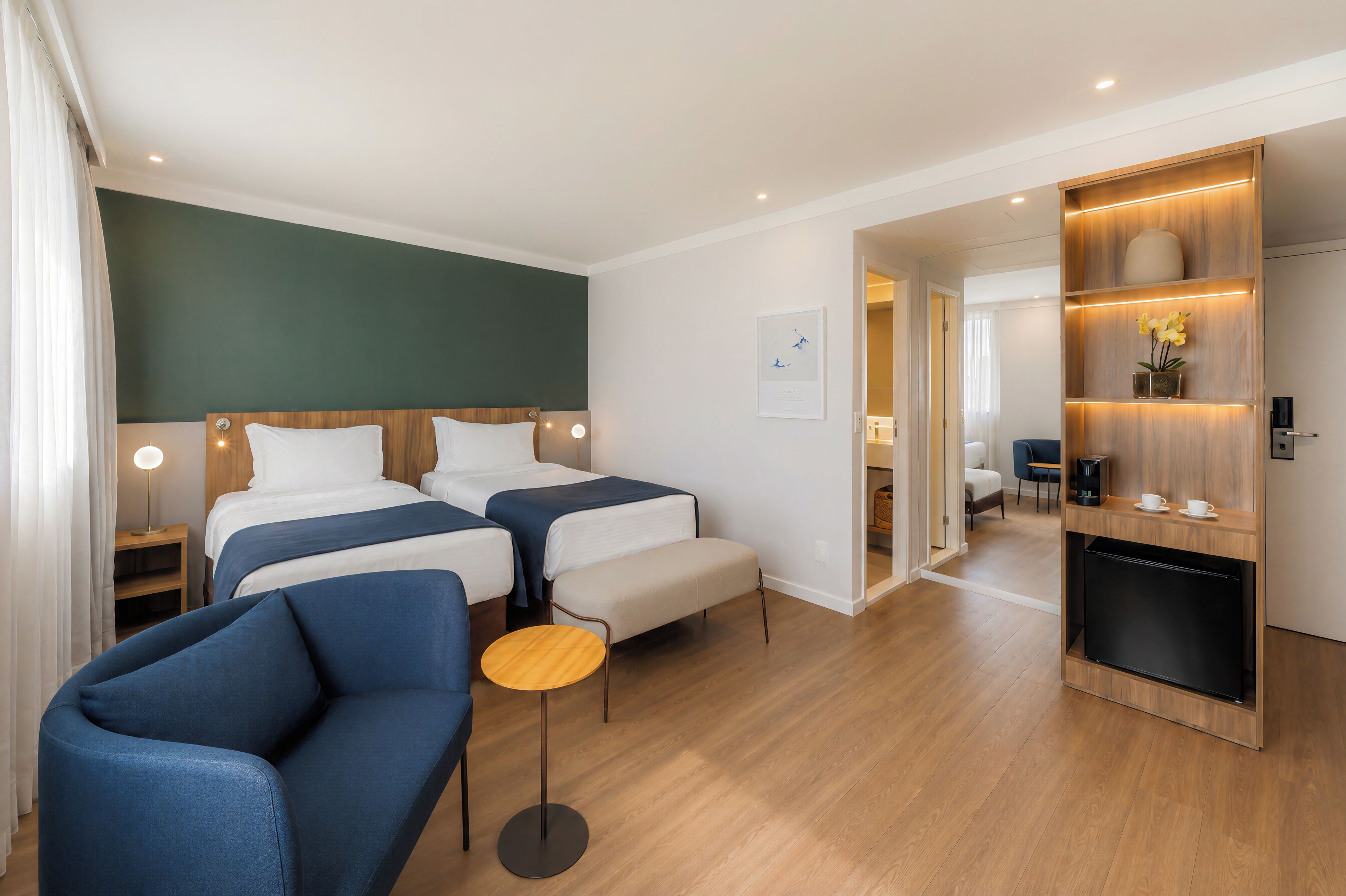 Een hotelkamer met twee bedden, een bank, een tafeltje en een kitchenette.