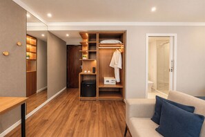 A compact hotel room with a walk-in closet, a small kitchenette, a shower area, and a seating area with cushions. - Blue Tree Premium Faria Lima (São Paulo)