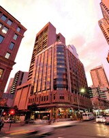 Ein modernes Hotel mit markanter Ecklage, großen Fenstern und einem gut sichtbaren Schild für das Metro Hotel Sydney Central.