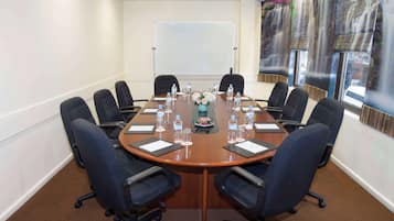Une salle de conférence équipée d’une table ronde, de huit chaises, de bouteilles d’eau et d’un arrangement floral en guise de décoration centrale.