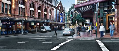 A street view with a Metro Hotel Marlow building, a pedestrian crossing, and a traffic light.