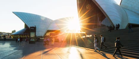 A modern architectural structure with a unique design, featuring large, curved surfaces and a spacious plaza in front.