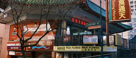 A street view with a building featuring a traditional roof and signage for 'Harbour Arcade' and 'Milk Flower'.