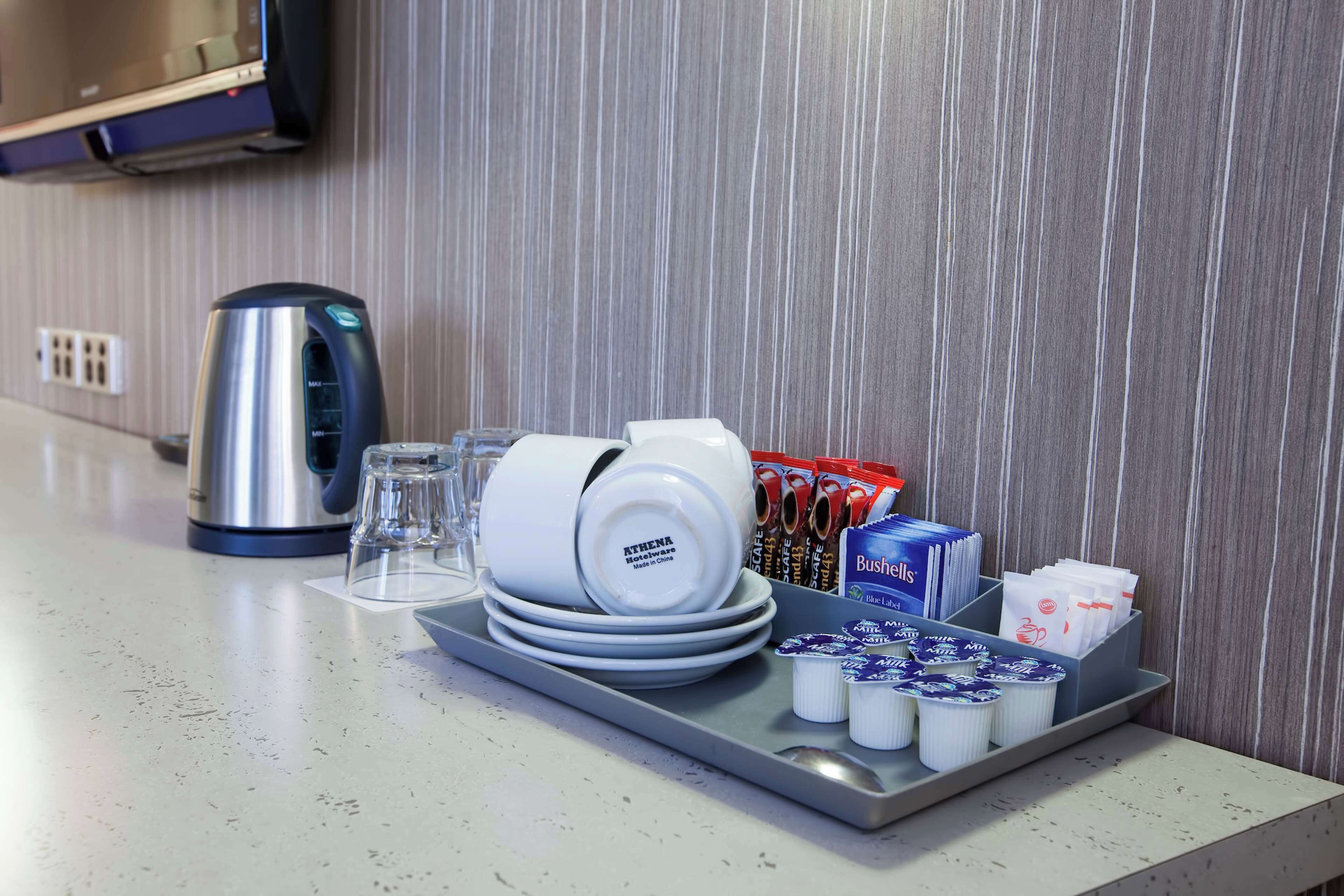 A kitchen counter with a tray holding stacked plates, a kettle, and condiments.