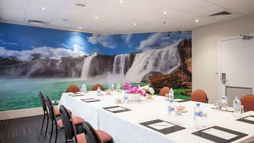 A conference room with a waterfall mural, a white tablecloth, and orange chairs.