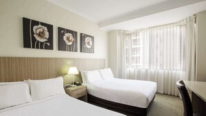 A hotel room with two beds, a desk, a lamp, and three flower paintings on the wall. - Metro Hotel Marlow Sydney Central (Haymarket)