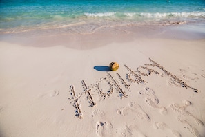 A sandy beach with footprints and the word "HOLIDAYS" written in the sand.