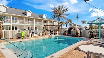 Relax by the pool surrounded by lounge chairs and umbrellas, with a gazebo and palm trees nearby.
