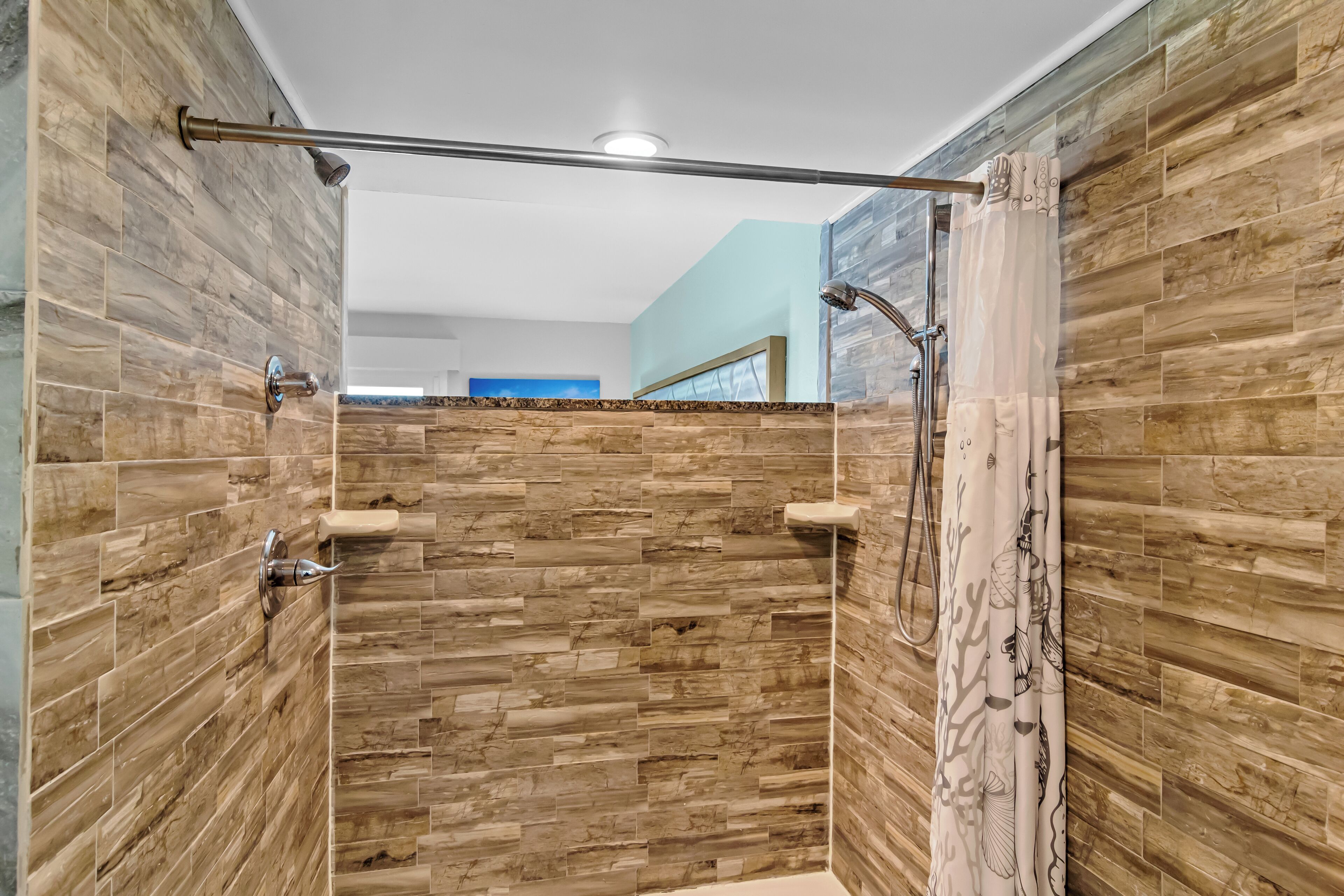 Una ducha moderna con diseño de pared de madera, puerta de cristal y cabezal metálico.