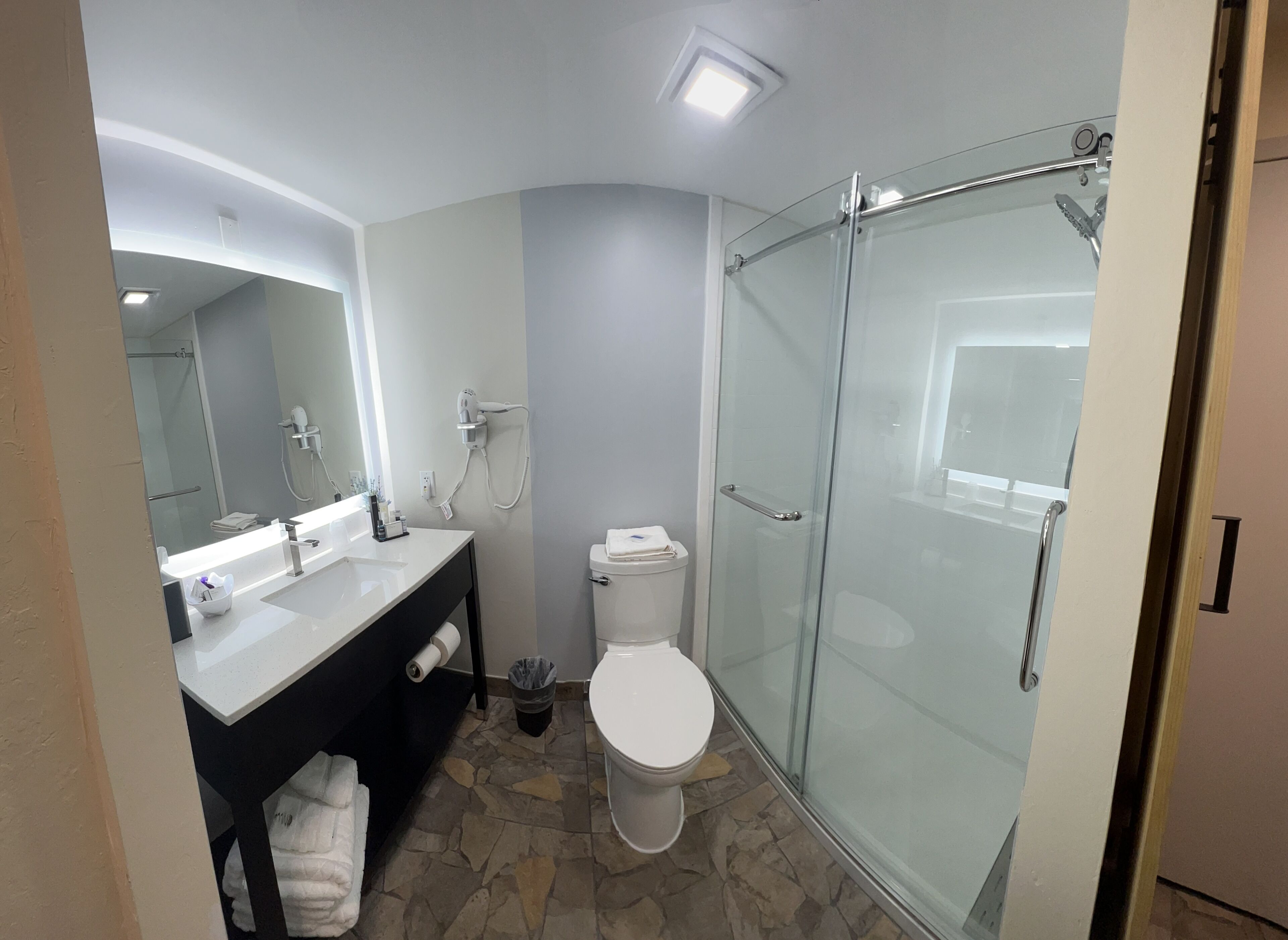 Un bagno moderno con cabina doccia in vetro, un water bianco e un mobile lavabo con specchio.
