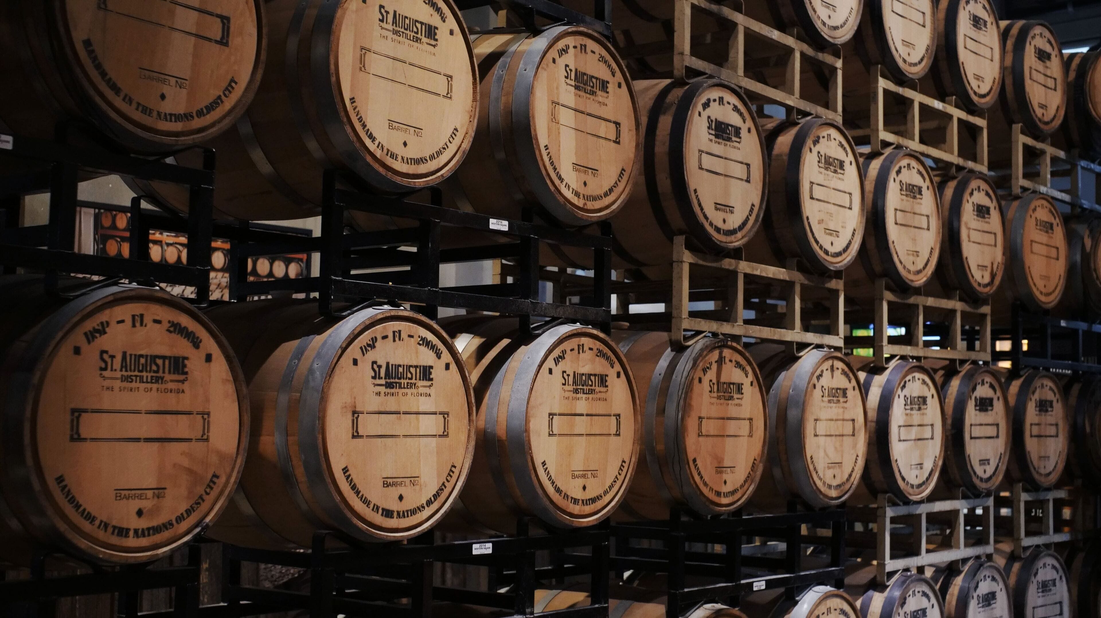 Wooden barrels stacked on shelves in a warehouse.