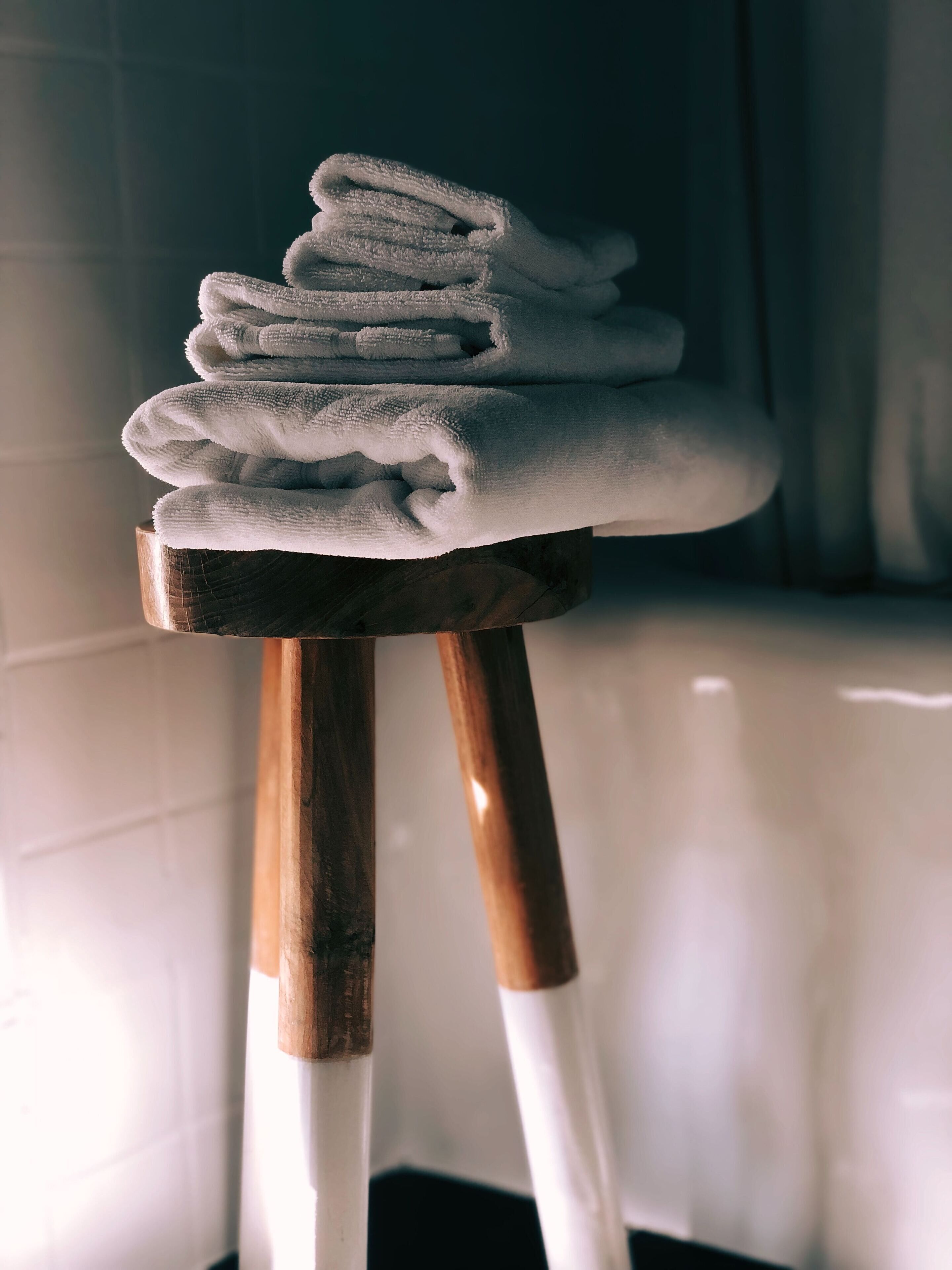 Un montón de toallas blancas sobre un perchero de madera en un baño.