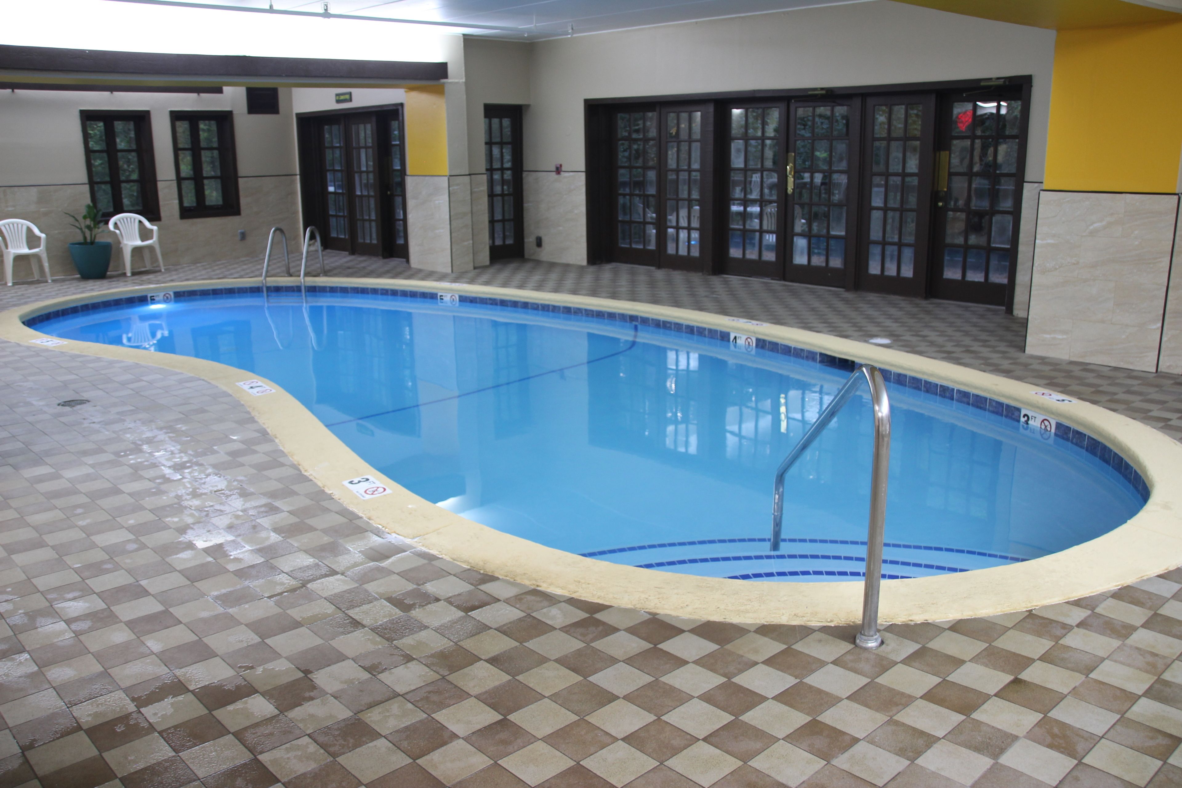 Una piscina interior con suelo a cuadros, una escalera y una puerta que da a otra habitación.