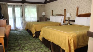 Habitación de hotel con dos camas, un escritorio, una silla y un ventanal con cortinas.