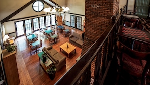 A spacious dining area with high ceilings and large windows, featuring wooden tables and chairs.