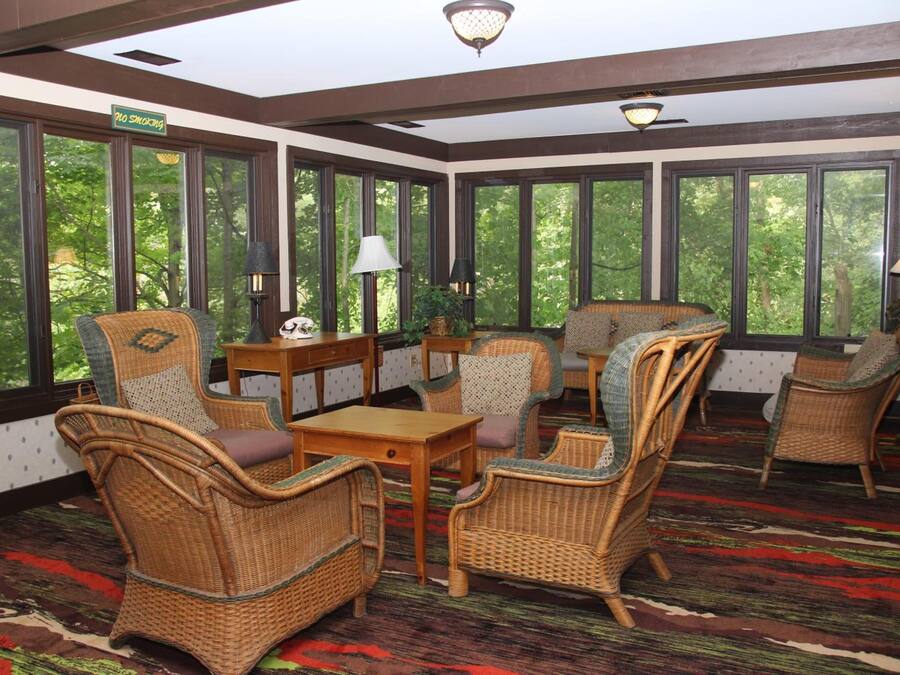 A sunroom with wicker furniture, large windows, and a patterned carpet.