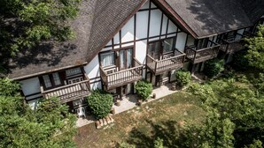A traditional half-timbered house with multiple balconies, a well-maintained garden, and a clear view of the surrounding greenery.