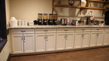 A kitchen with white cabinets, a granite countertop, and various kitchen appliances.
