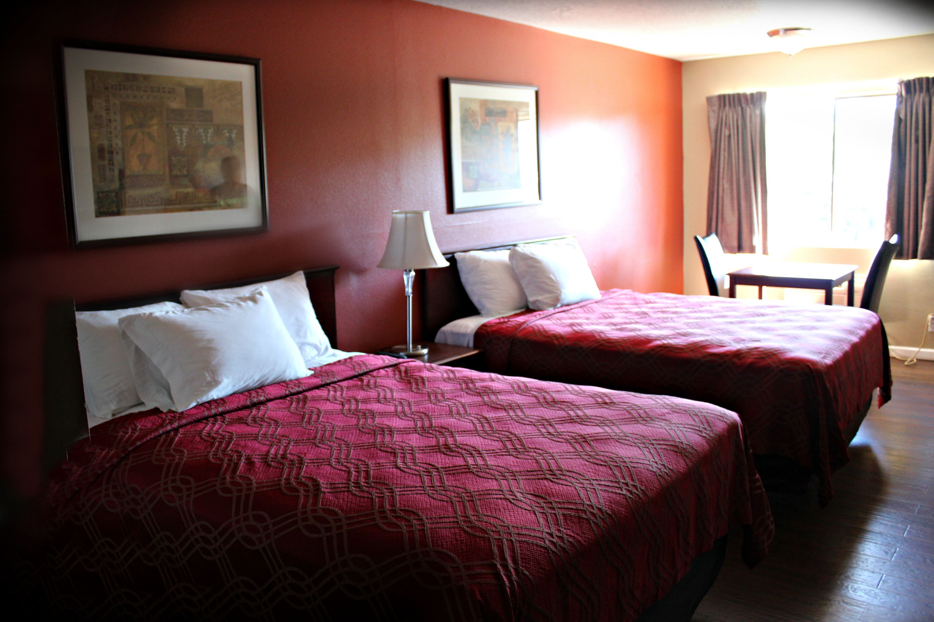 A hotel room with two beds, a desk, and a chair.
