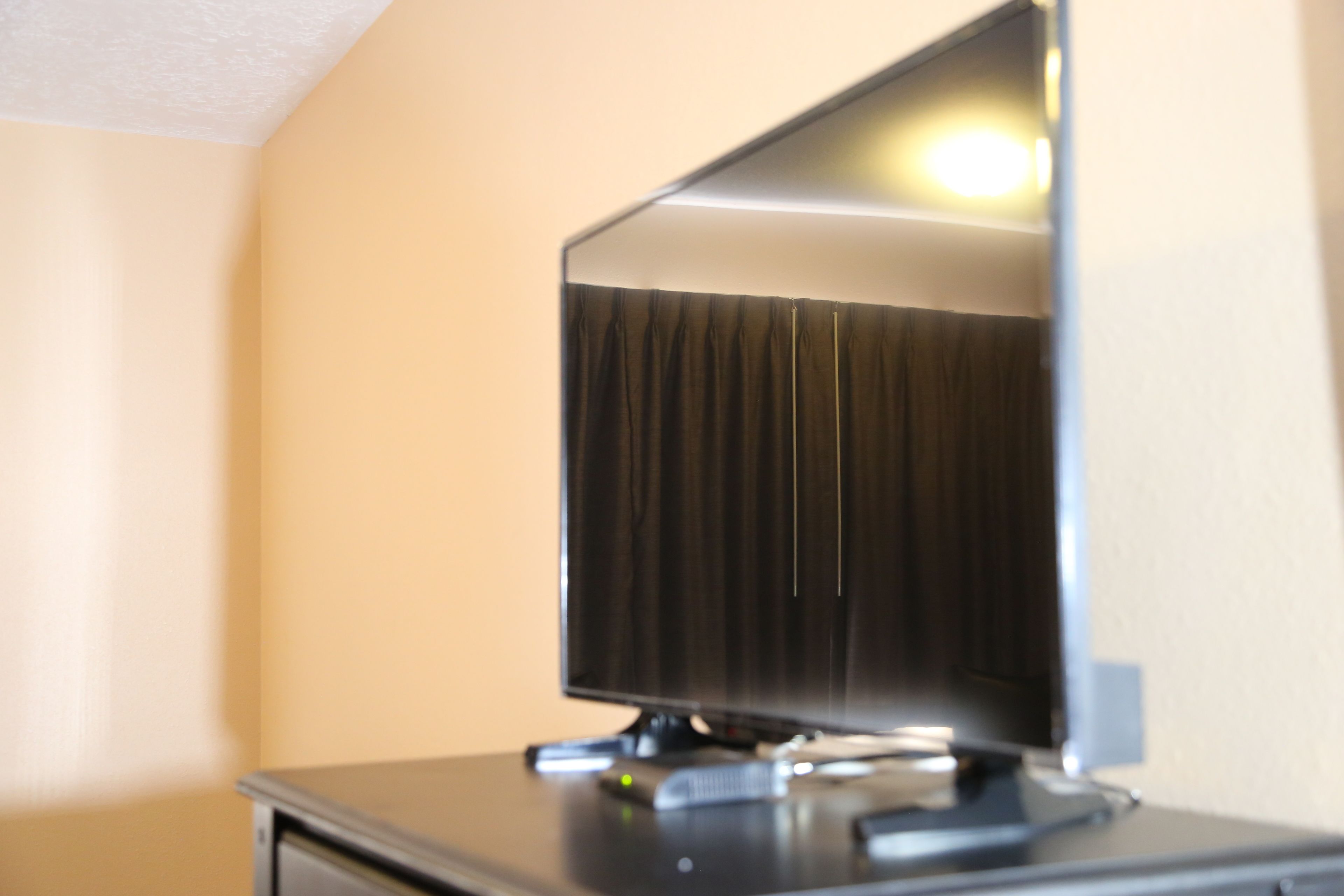 A television on a stand in a room with beige walls.