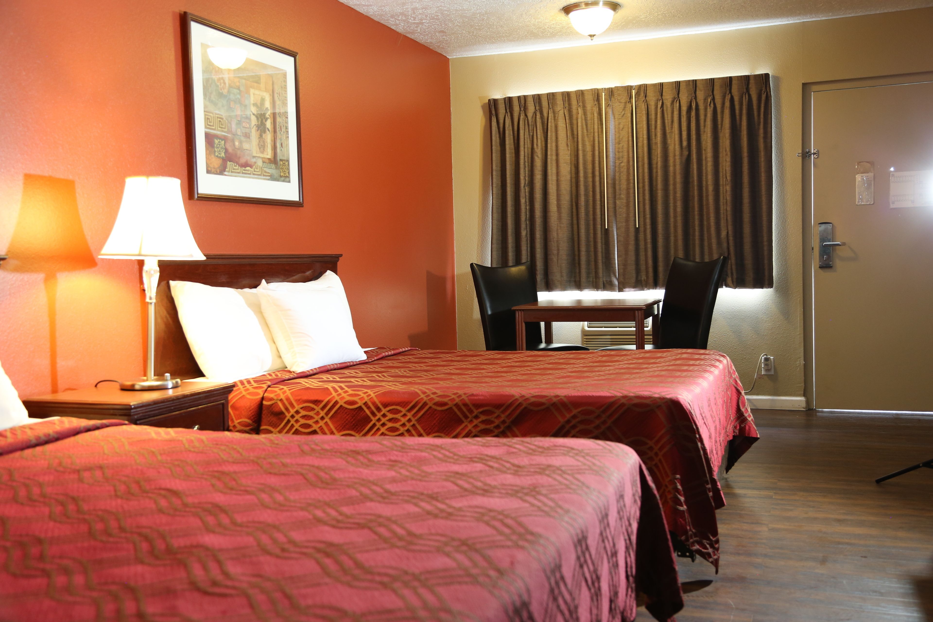 A hotel room with two beds, a desk, and a chair.