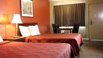 A hotel room with two beds, a desk, and a chair.