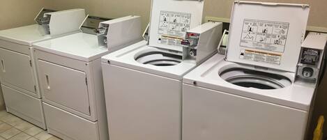 A laundry area with three washing machines and a dryer.