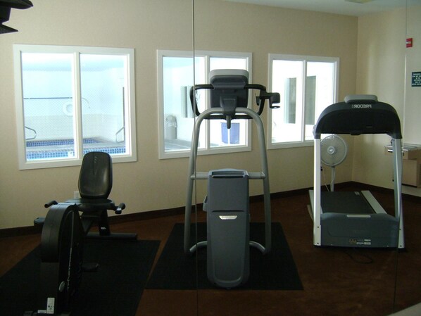 A gym with cardio machines, a rowing machine, and a treadmill. - Aspen Hotel Soldotna (Soldotna)