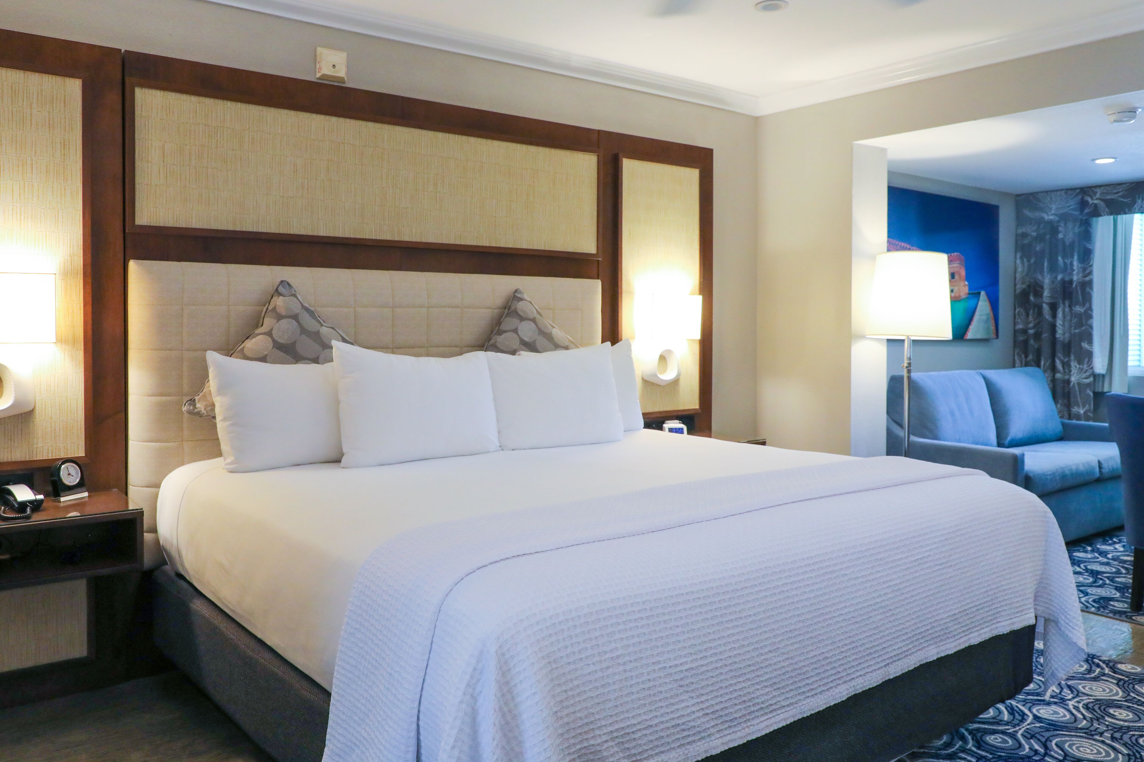 Una habitación de hotel con una cama grande, dos mesitas de noche, un escritorio y una silla.