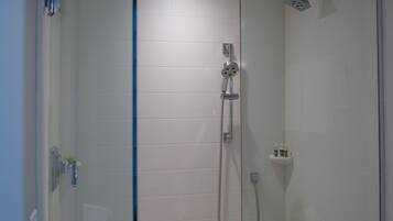 A modern shower with a glass door, a handheld showerhead, and a wall-mounted faucet.