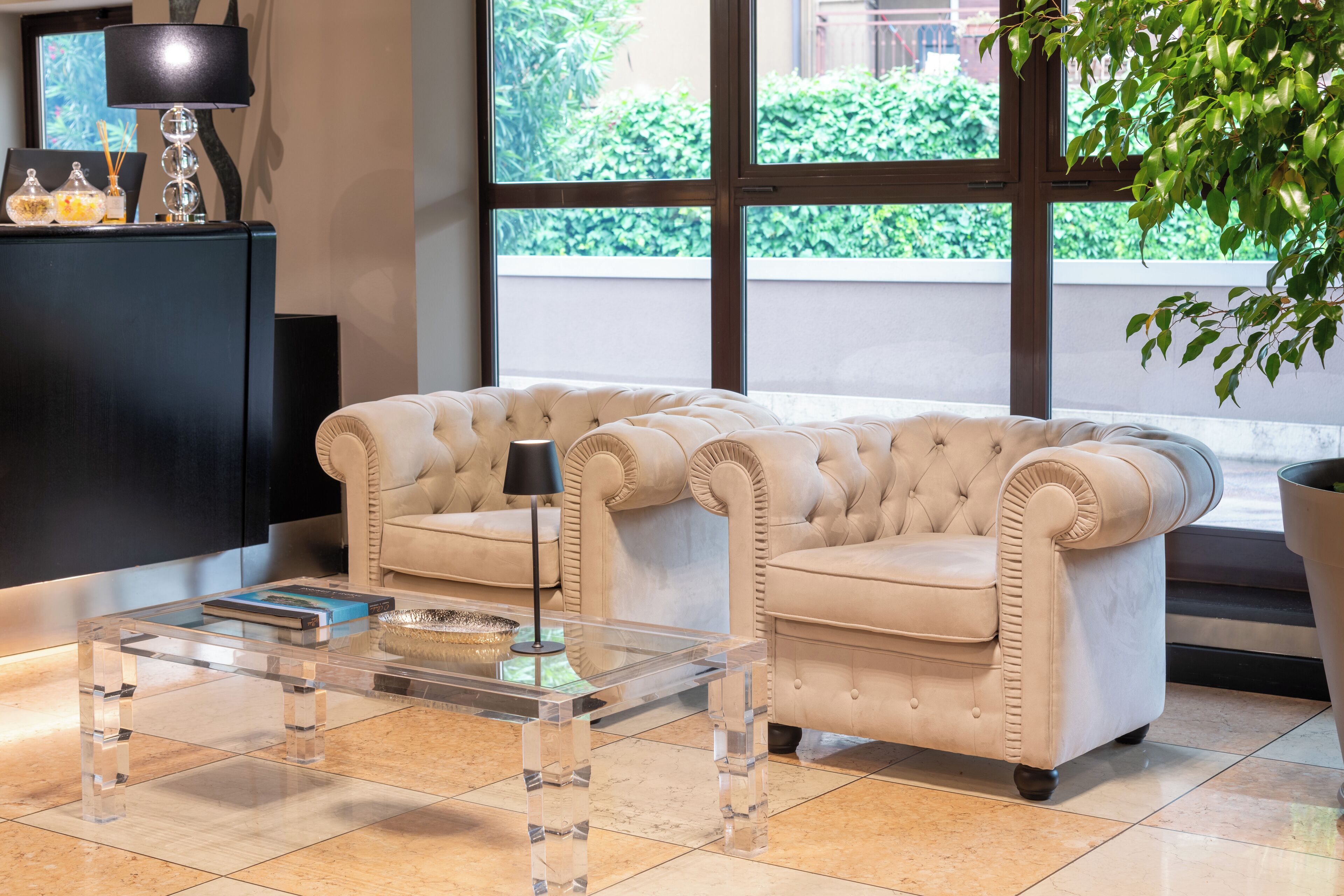 A living room with a beige sofa, a glass coffee table, and a black lamp.