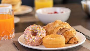 Een ontbijtbord met een roze glazuurdonut, een gewone donut en een croissant.