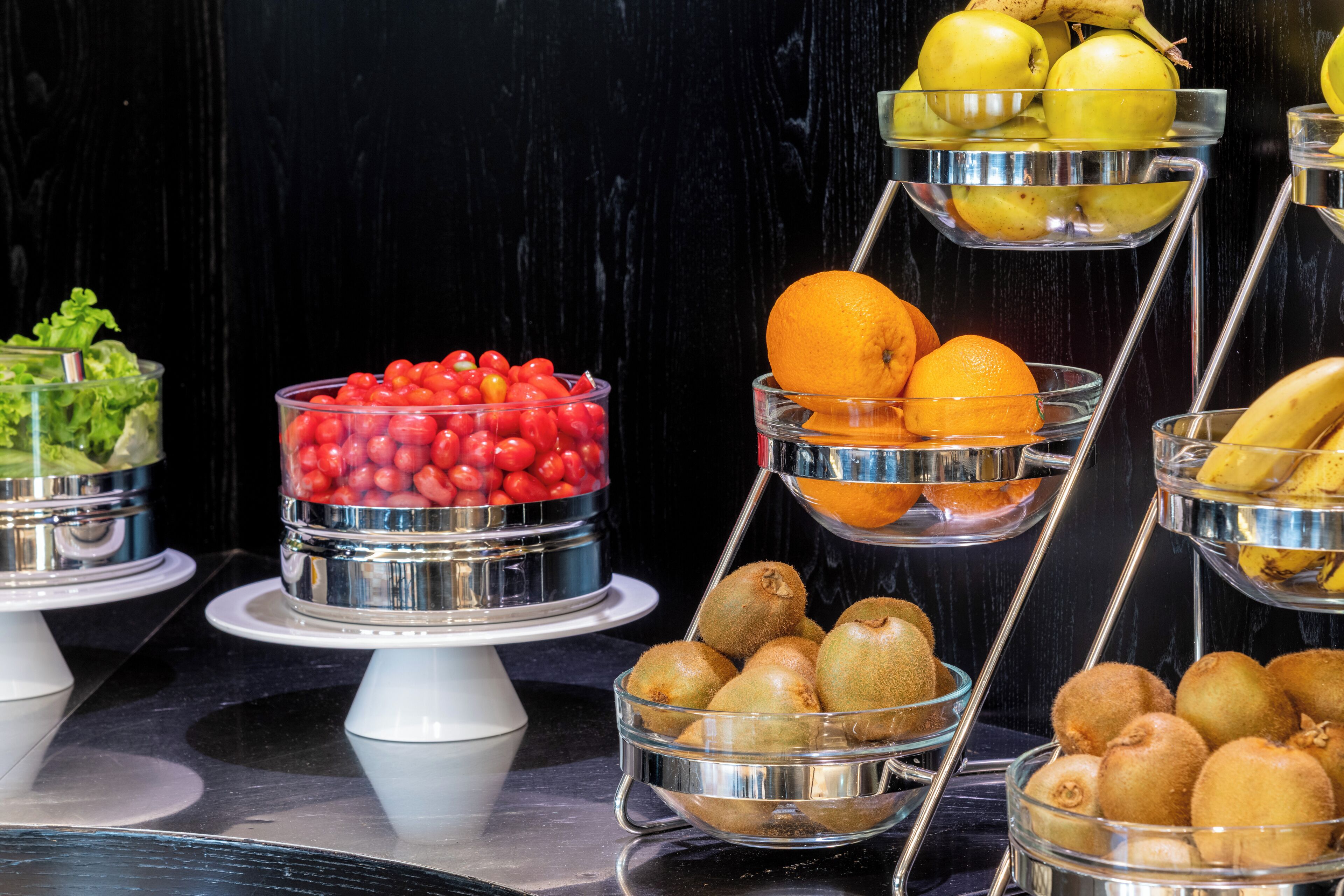 Un buffet proposant une variété de fruits et de légumes présentés dans des récipients en verre.